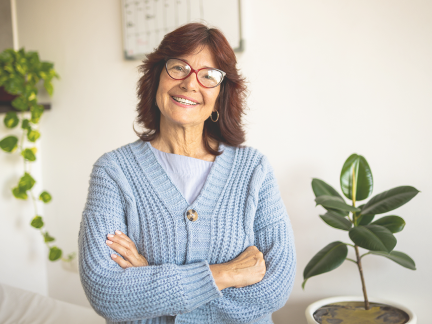 Confident mature woman wearing glassing smiling at camera wearing a blue cardigan.