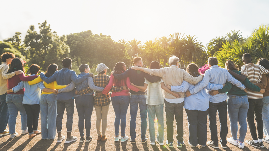 Group of multigenerational people hugging each others - community, social support, multiracial and diversity.