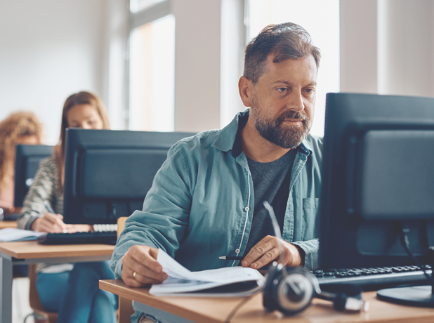 Mature male student using desktop PC while learning in the classroom.