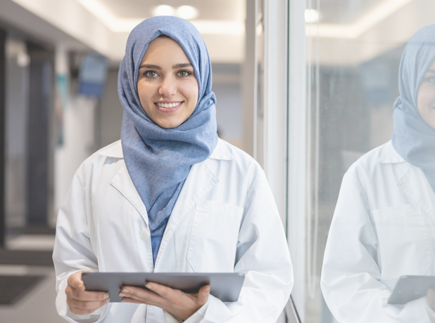 Lady at work holding a tablet and smiling at the camera.<br />
