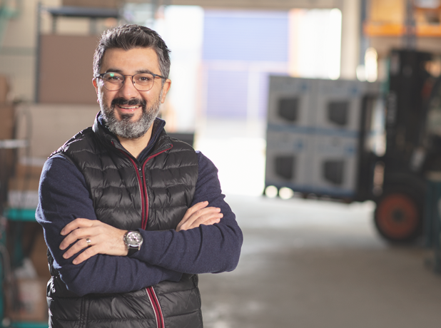 Adult man in factory looking at the camera and smiling.
