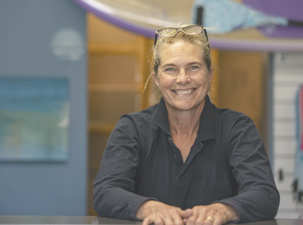 A shot of a mature woman stood at the desk of a surf shop in Perth, Australia.