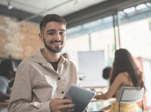 Young man in office looking at the camera and smiling.
