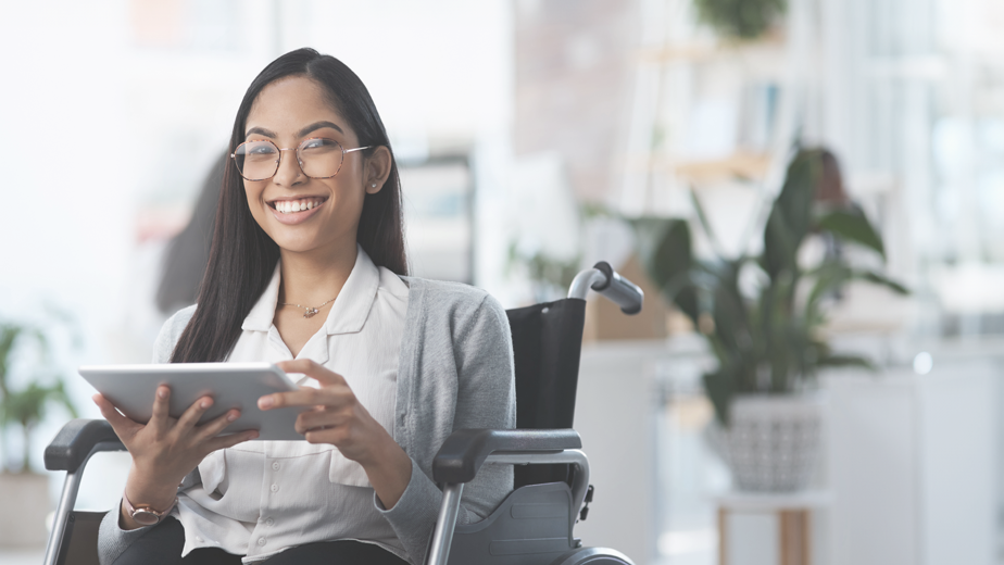 Portrait of a young businesswoman in a wheelchair using her tablet in an office environment.
