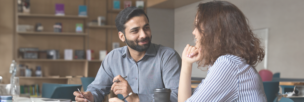 Interview of happy smiling Indian worker and young professional providing friendly support and discussing job resume.
