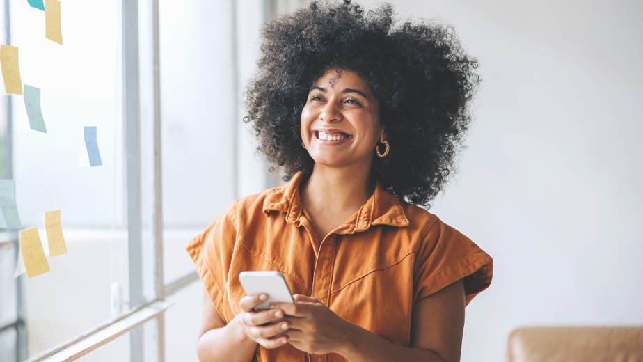 Pensive businesswoman holding a smartphone in a creative office.