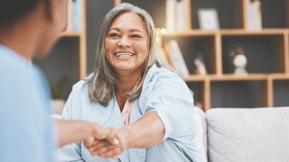 Mature aged woman shaking hands with a male businessman in a meeting.