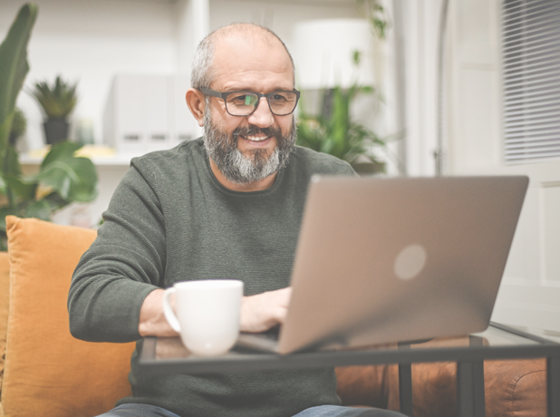 Mature man working from home on laptop wearing glasses.