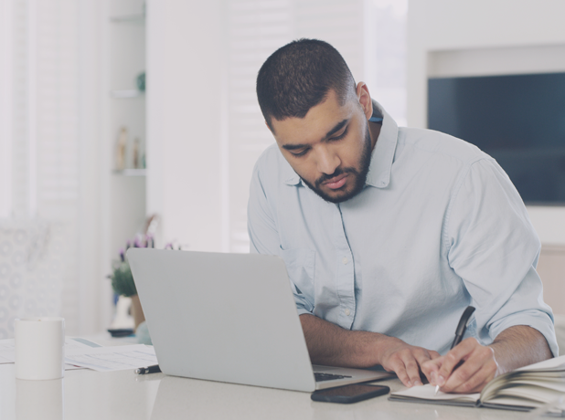 Middle Eastern man working on financial documents at his desk.