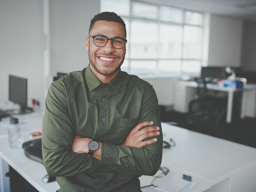 Portrait of a happy confident young african american businessman standing with his arms crossed looking at camera.