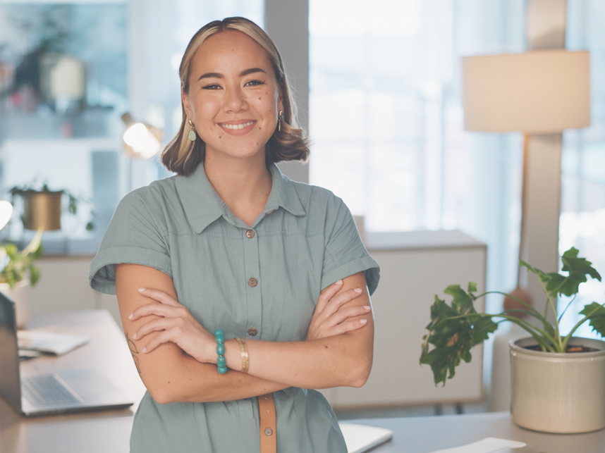 A young lady in a casual office environment smiling and looking at the camera.