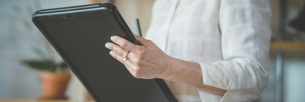 Mid-torso shot of woman in white shirt holds a report document