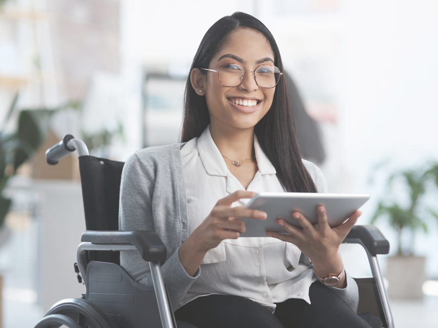 Portrait of a young businesswoman in a wheelchair using her tablet in an office environment.