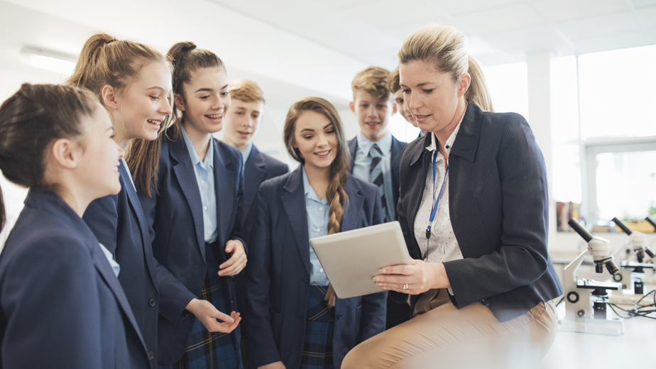 A female teacher talking to a group of students in a science room.