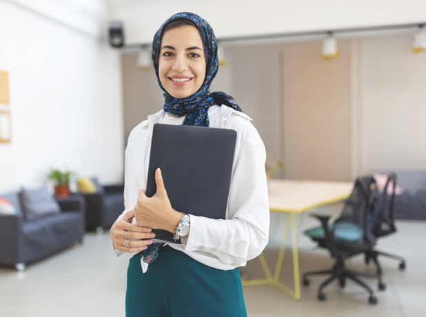 Portrait of a middle eastern businesswoman at office. Woman executive wearing headscarf smiling at camera holding a file.