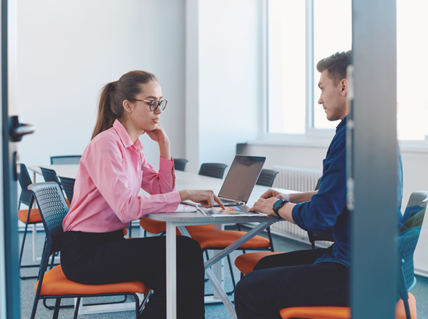 In a sleek and modern office a female discusses her business plan with a a male business advisor.