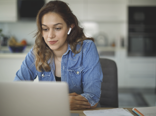 Smiling young woman with bluetooth headphones attends an online course at home