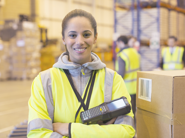 young woman in high vis smiling at camera standing in warehouse