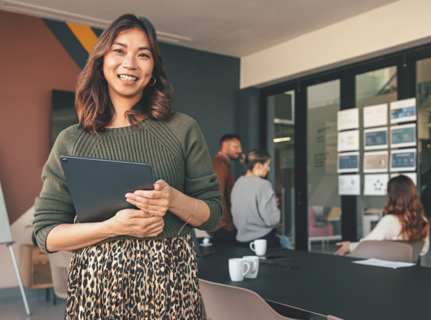 Happy Asian businesswoman smiling at the camera in a boardroom.