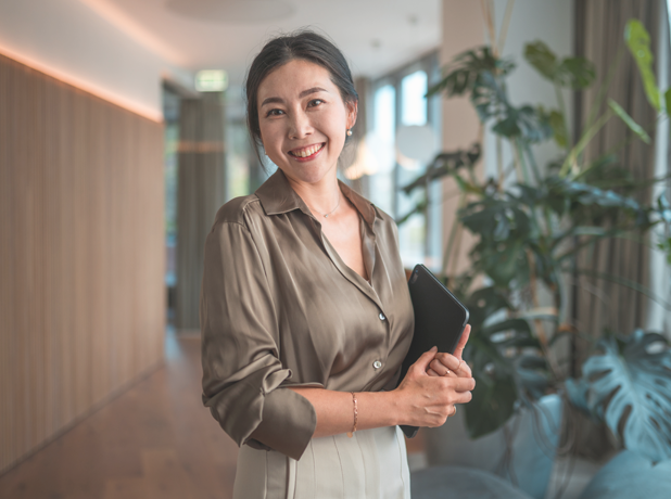 Smiling Female Korean Corporate Employee with Digital Device smiling to camera. 