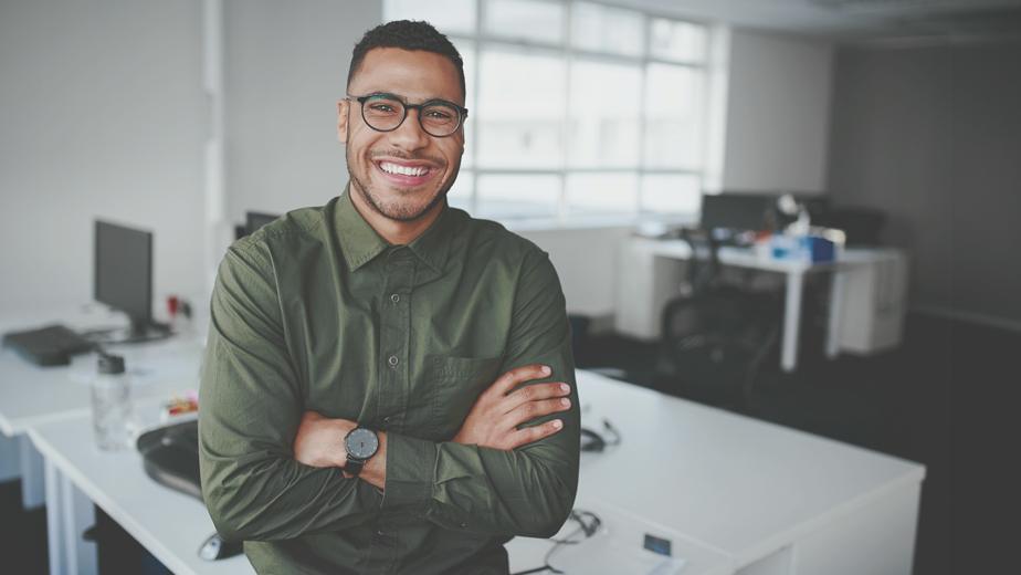 Portrait of a happy confident young african american businessman standing with his arms crossed looking at camera.