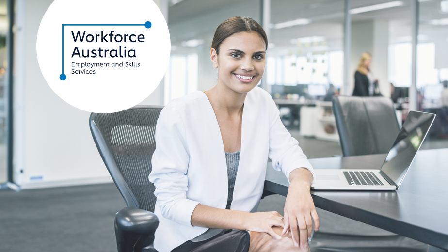 Business woman at desk looking at the camera and smiling.