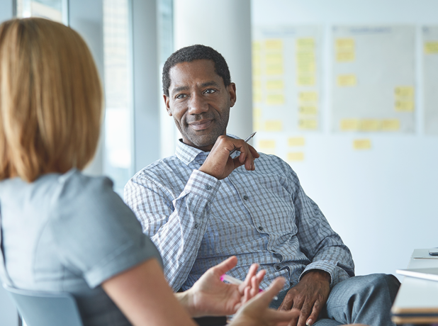 African male having an in-depth discussion with female colleague in a workpalce. 