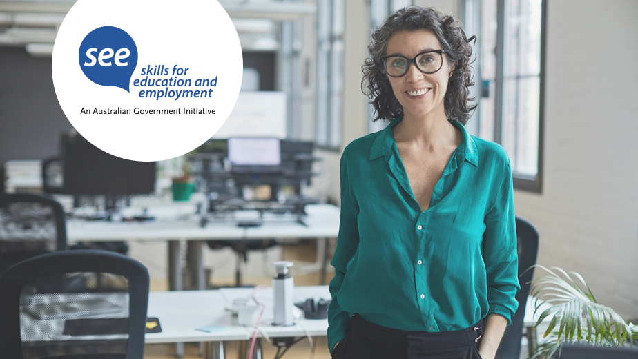 A businesswoman standing in modern workplace smiling. 