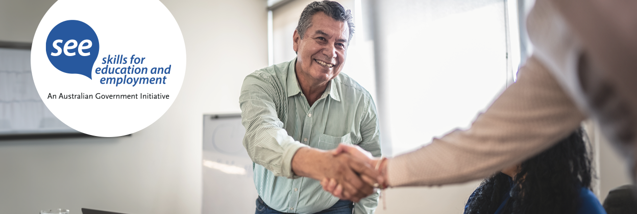 Middle Aged man in a work environment shaking hands with a fellow colleague. Includes Skills for Education and Training logo. 