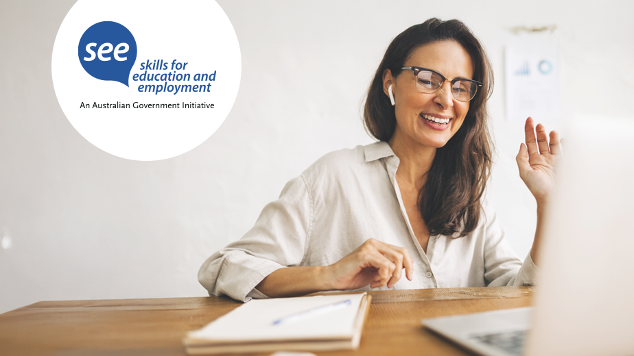 Middle-aged woman wearing glasses smiling and looking at computer while studying. 